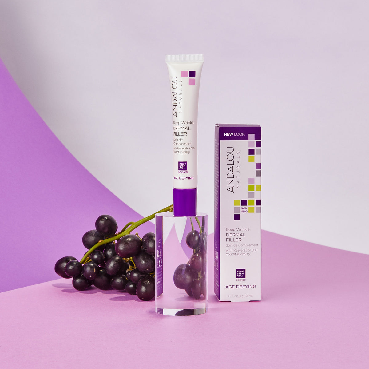 A tube of Age-Defying Deep Wrinkle Dermal Filler, placed beside grapes on a glass.