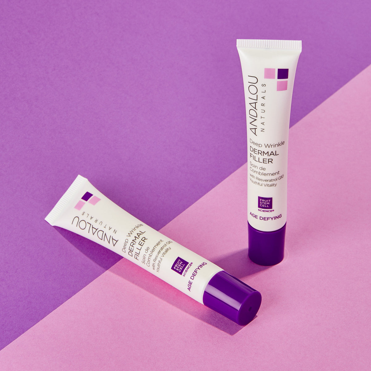 Two tubes of Age-Defying Deep Wrinkle Dermal Filler from Andalou Naturals on a pink and purple background.